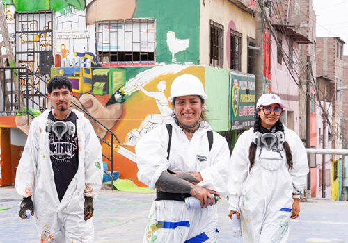 tres personas pintando murales con ropa de protección contra pintura